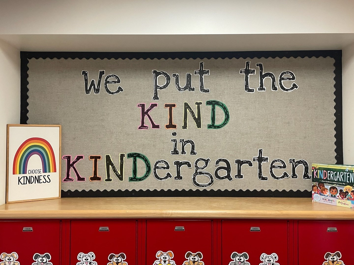 Black board, tan background of a bulletin board with we put the kind in Kindergarten written on it in multiple colors