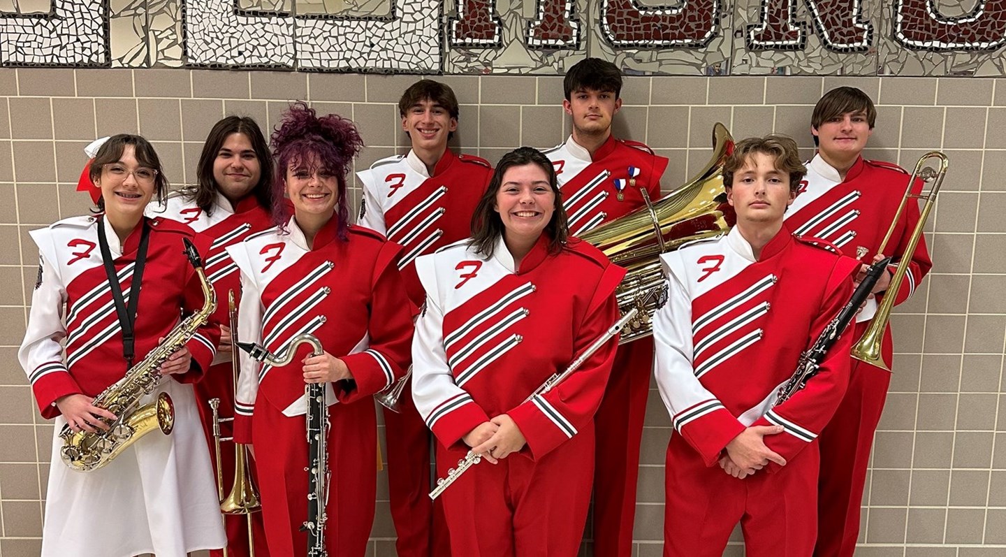 Band students with red and white uniforms against a gray tile background