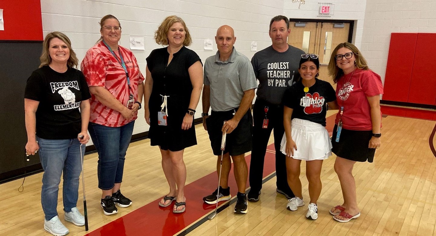 Gym.  Teachers holding golf clubs