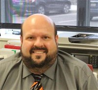 John Capehart. Bald head, beard in a gray shirt